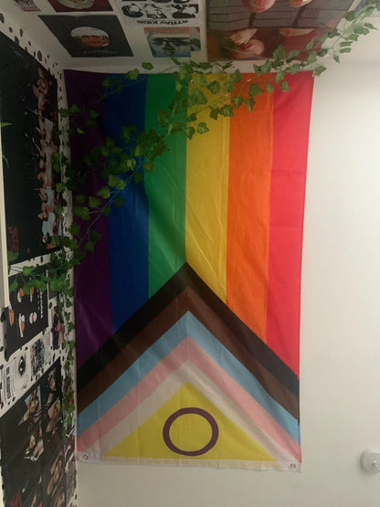 Pride Progress Rainbow flag hanging on a wall with a decorative corner.